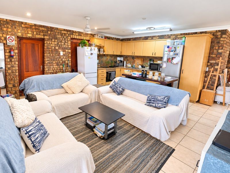 Spacious open-plan living and kitchen area featuring exposed brick walls, tiled flooring, and functional built-in cabinetry.