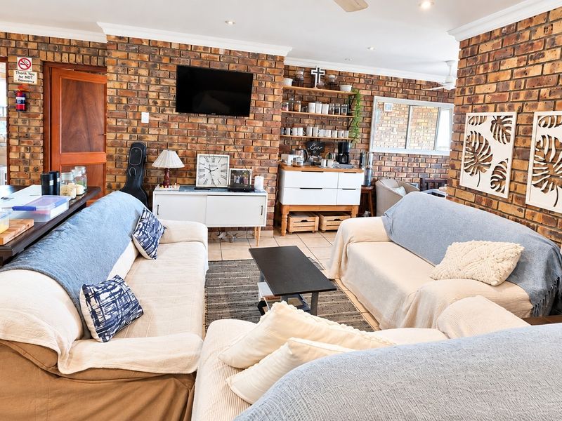 Spacious living area featuring distinctive exposed brick walls, tiled flooring, and recessed downlighting, creating a warm and textured atmosphere.