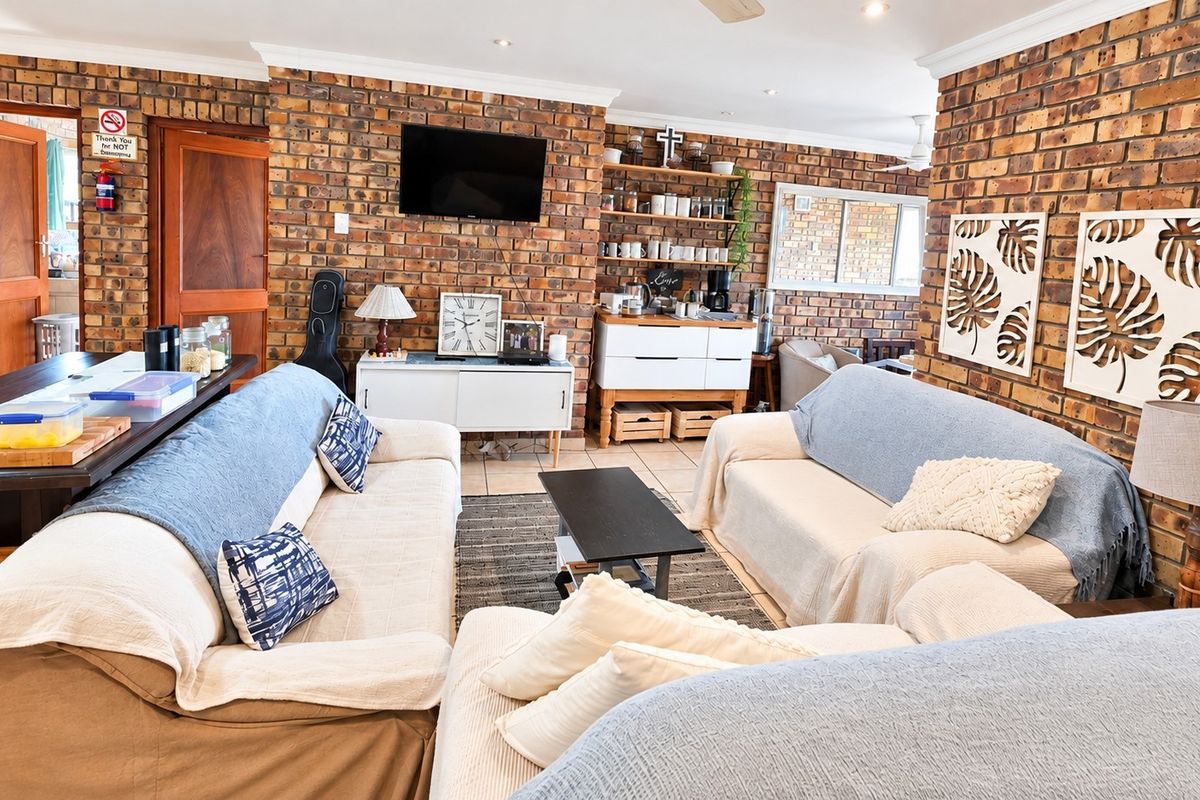 Spacious living area featuring distinctive exposed brick walls, tiled flooring, and recessed downlighting, creating a warm and textured atmosphere.