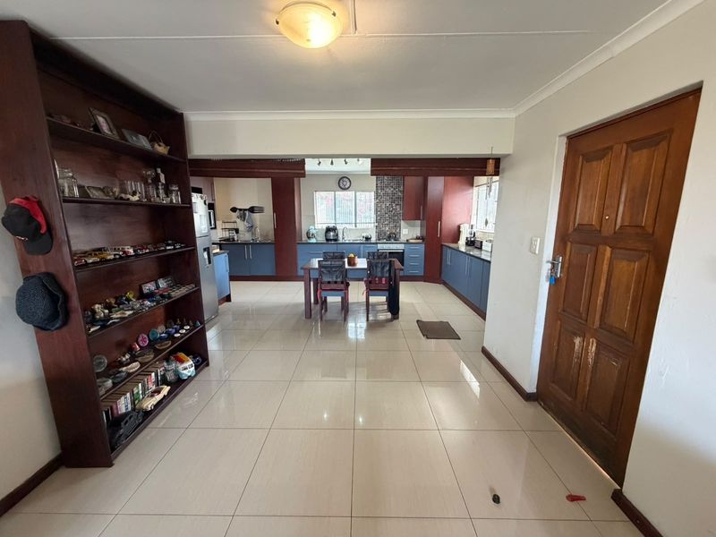 Open-plan living and kitchen area featuring tiled floors, modern blue cabinetry, built-in appliances, and a solid wood entrance door.