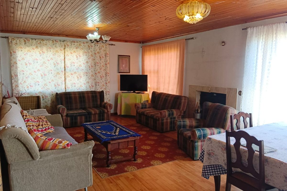 Spacious living area featuring a timber-clad ceiling, laminate flooring, and a traditional fireplace with a stone surround.