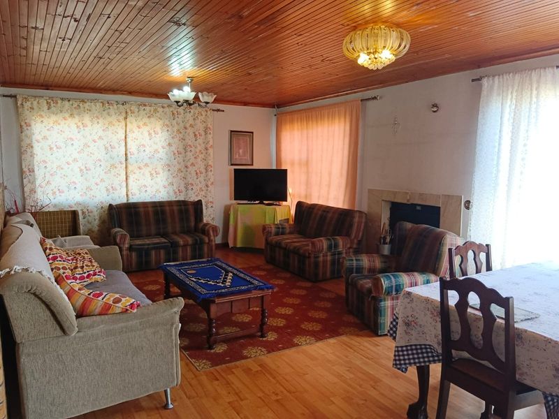 Spacious living area featuring a timber-clad ceiling, laminate flooring, and a traditional fireplace with a stone surround.