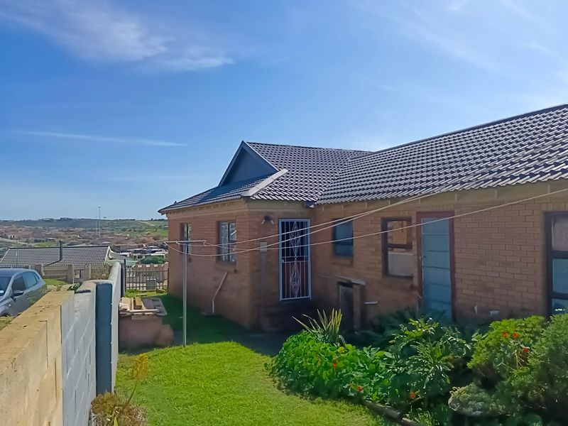 Rear view of a face brick house featuring a tiled roof, security gate, and a private garden area with boundary walling.
