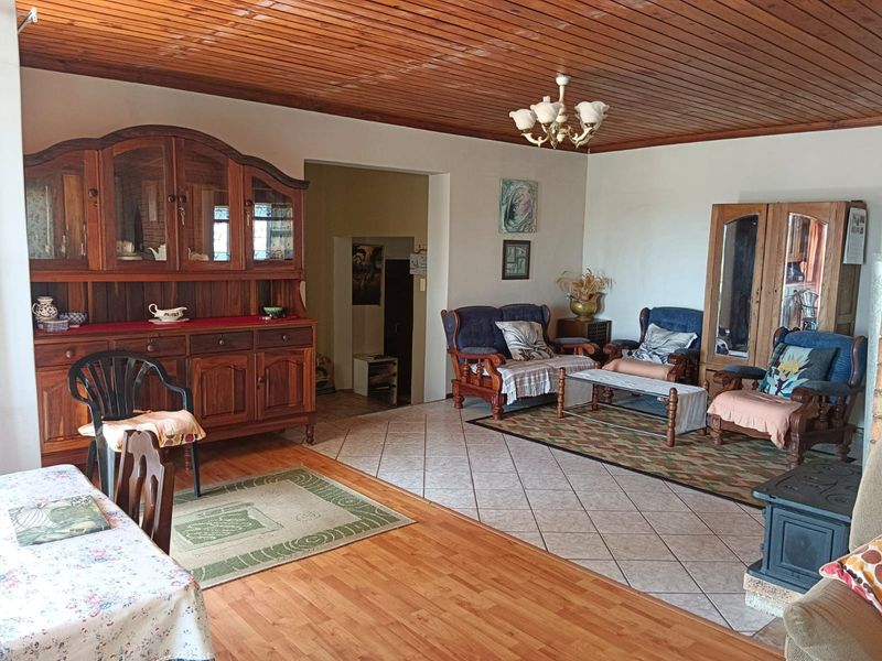 Spacious open-plan living area featuring a timber-clad ceiling, a mix of laminate and tiled flooring, and a built-in cast iron fireplace.