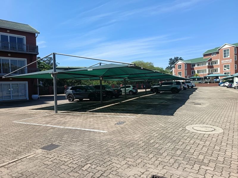 A well-maintained paved parking area at Nkwazi Office Park featuring covered shade cloth parking bays for vehicles.