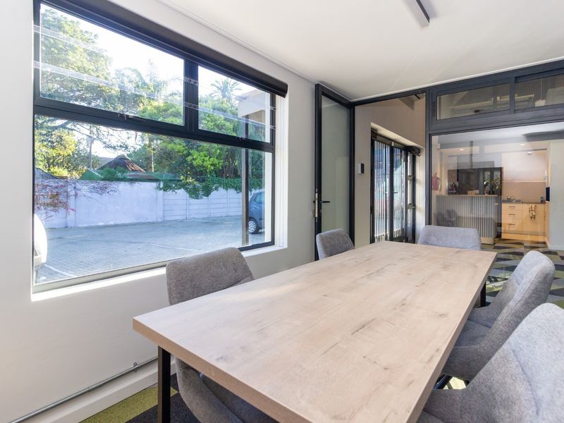 Modern office meeting room featuring large windows, glass partitioning, and contemporary patterned carpeting, offering a bright and professional workspace environment.