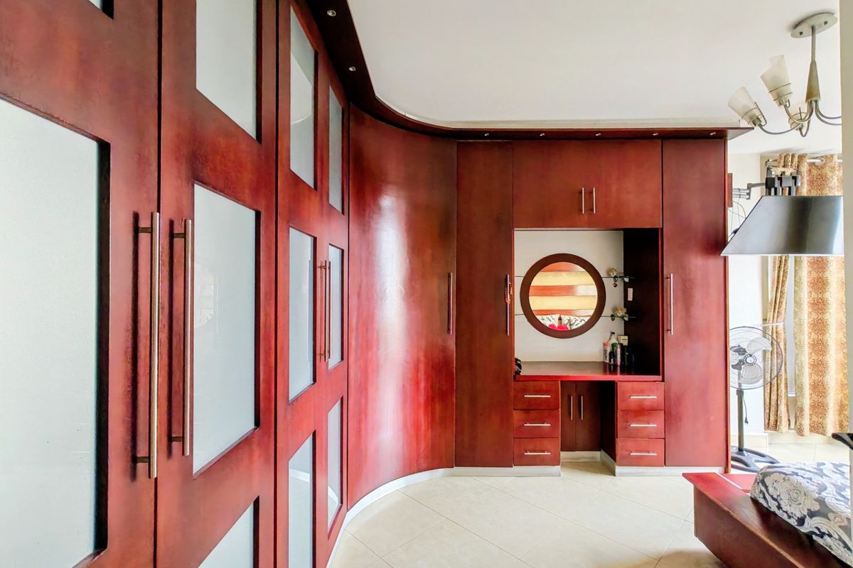 A bedroom featuring extensive custom built-in cabinetry with integrated vanity, frosted glass accents, and polished tile flooring.