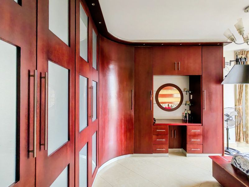 A bedroom featuring extensive custom built-in cabinetry with integrated vanity, frosted glass accents, and polished tile flooring.