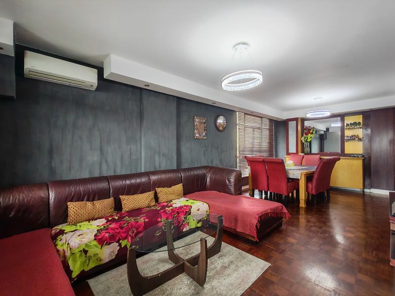 Spacious open-plan living and dining area featuring dark parquet flooring, a feature wall, and modern pendant lighting.