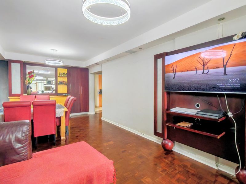 Open plan living and dining area featuring dark parquet flooring, built-in media cabinetry, and modern circular pendant lighting.