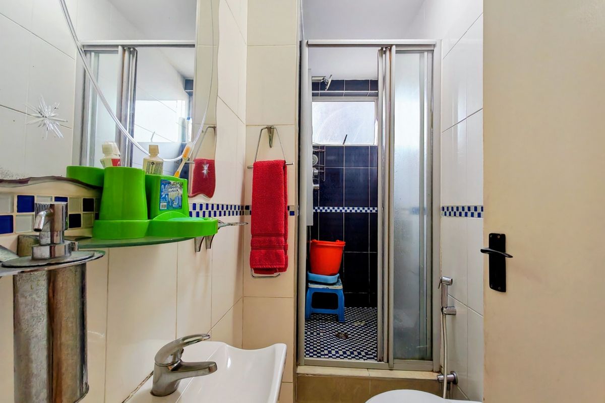 Compact bathroom featuring a shower enclosure, wall-mounted basin with mixer tap, and tiled finishes throughout.