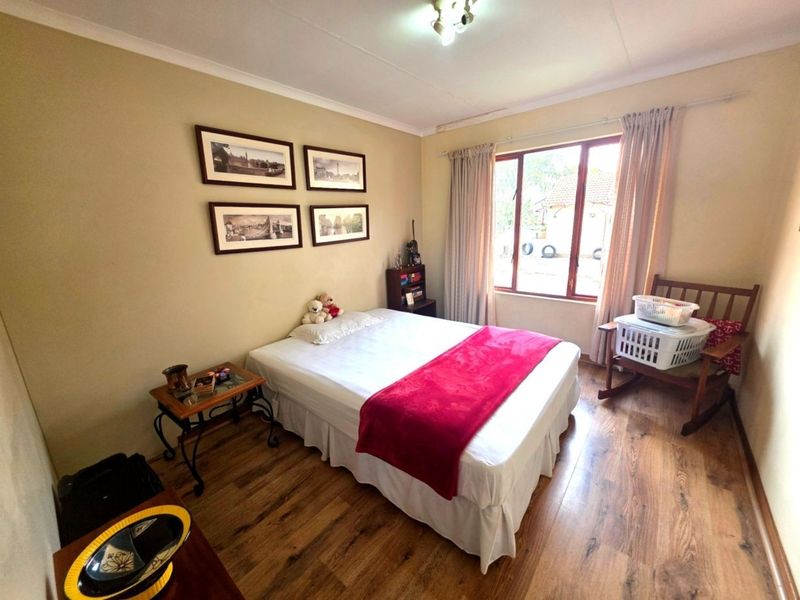A bedroom featuring laminate flooring, coved ceilings, and a window providing natural light.