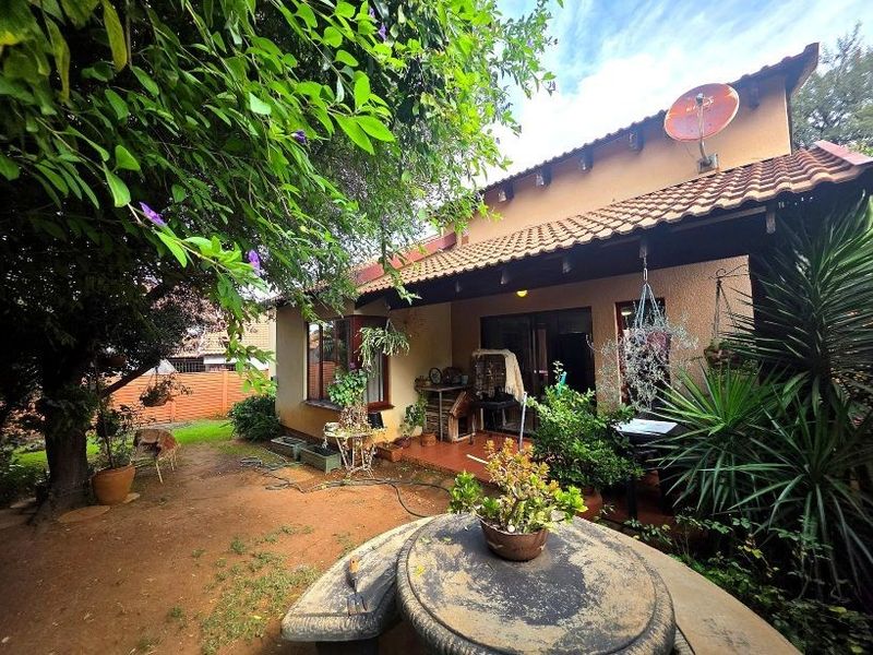 Rear view of the townhouse featuring a covered patio, tiled roof, and direct access to the garden area.