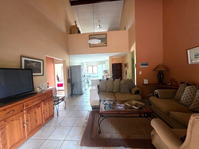 Spacious open-plan living area featuring high vaulted ceilings, tiled flooring, and a mezzanine level overlooking the main living space and kitchen.