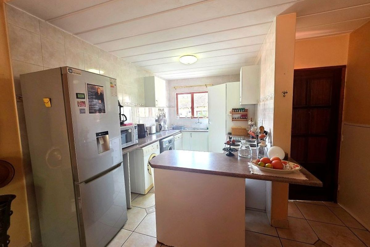 Functional kitchen featuring tiled flooring, ample cabinetry, a breakfast bar, and a tiled backsplash, offering a practical layout for daily meal preparation.