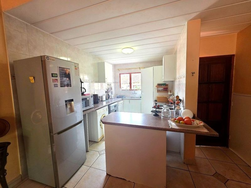 Functional kitchen featuring tiled flooring, ample cabinetry, a breakfast bar, and a tiled backsplash, offering a practical layout for daily meal preparation.