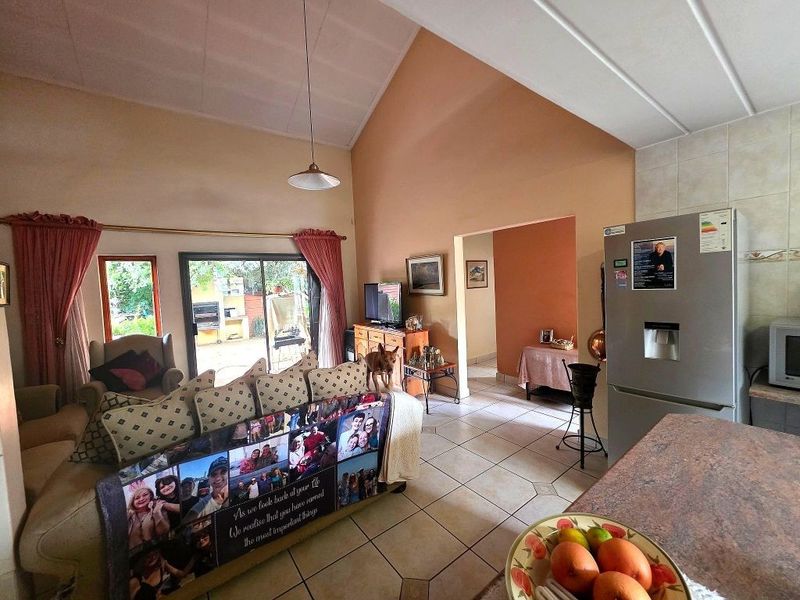 Open-plan living area featuring vaulted ceilings, tiled flooring, and direct access to the rear patio through sliding glass doors.