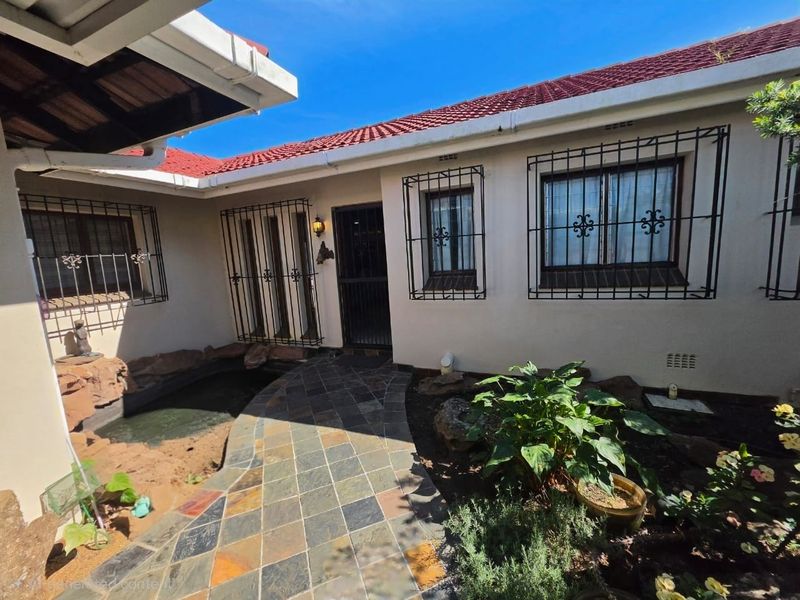 Front entrance area featuring a tiled walkway, security bars on windows, and a small built-in water feature.