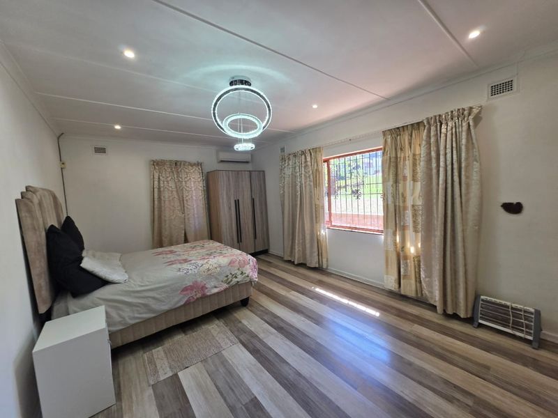Spacious bedroom featuring modern laminate flooring, split-system air conditioning, and secure window bars, offering a comfortable and well-lit living space.