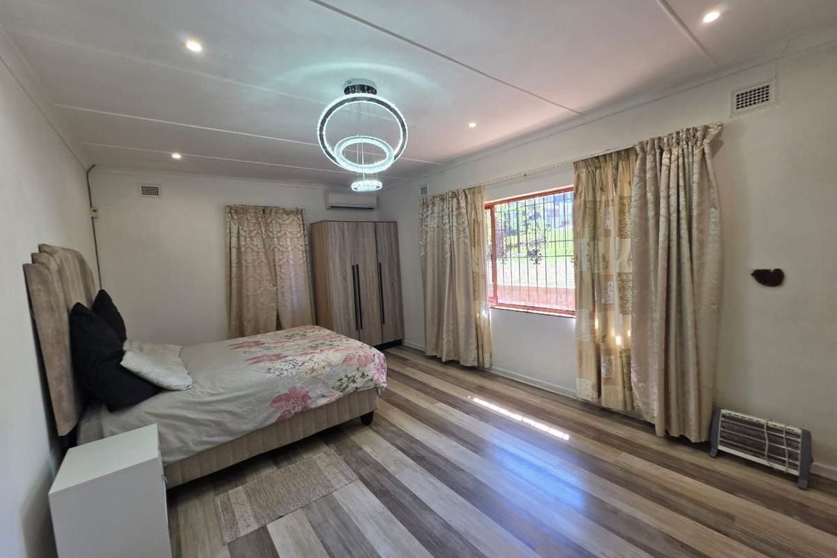 Spacious bedroom featuring modern laminate flooring, split-system air conditioning, and secure window bars, offering a comfortable and well-lit living space.