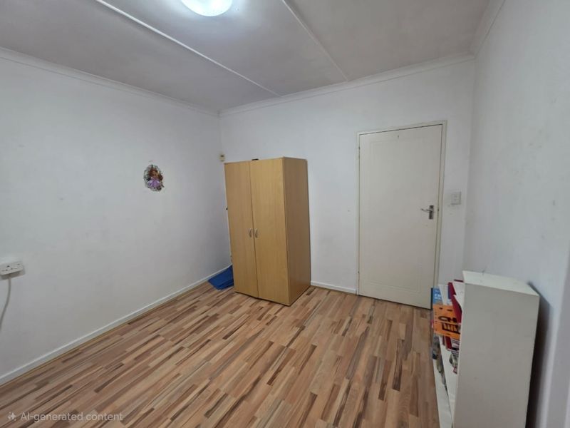 A simple bedroom featuring laminate flooring and white walls, offering a blank canvas for potential interior updates and personalization.