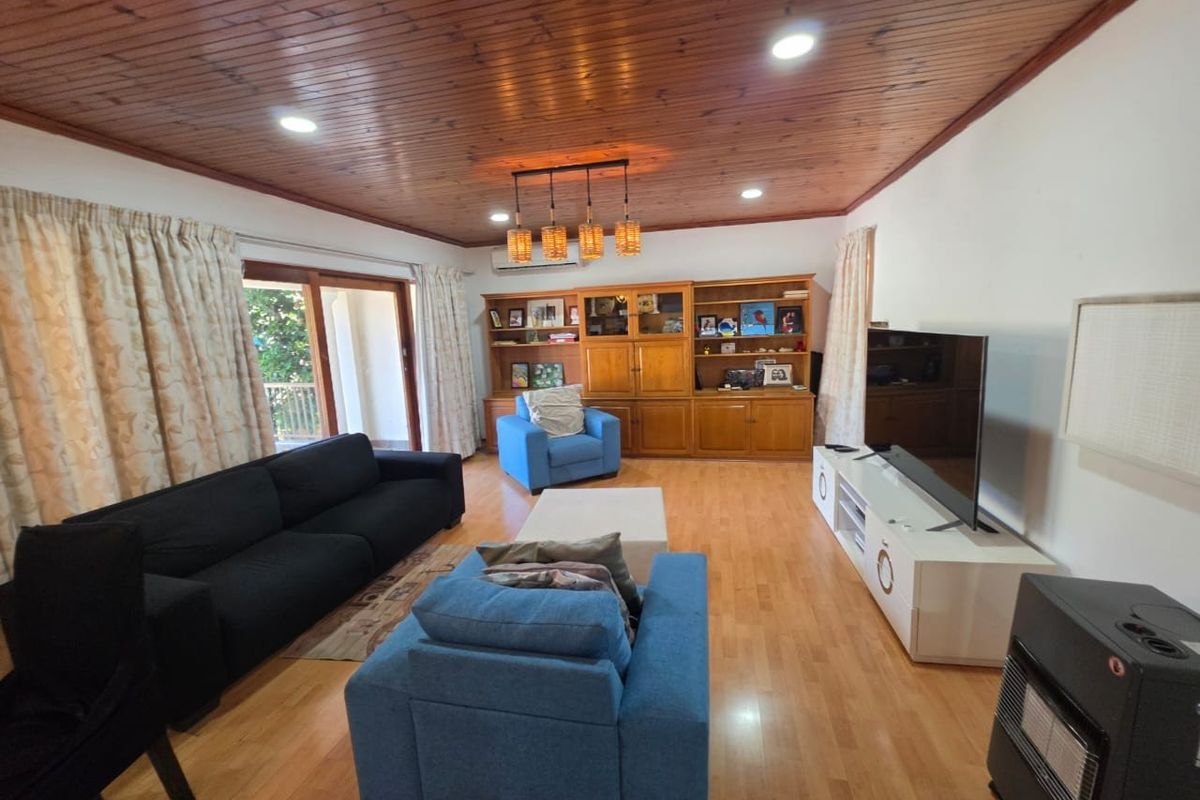 Spacious living room featuring warm timber ceilings, hardwood flooring, built-in cabinetry, and direct access to an outdoor area through sliding glass doors.