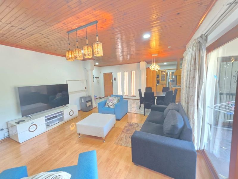 Spacious open-plan living and dining area featuring warm timber ceilings, laminate flooring, and large sliding glass doors providing natural light.