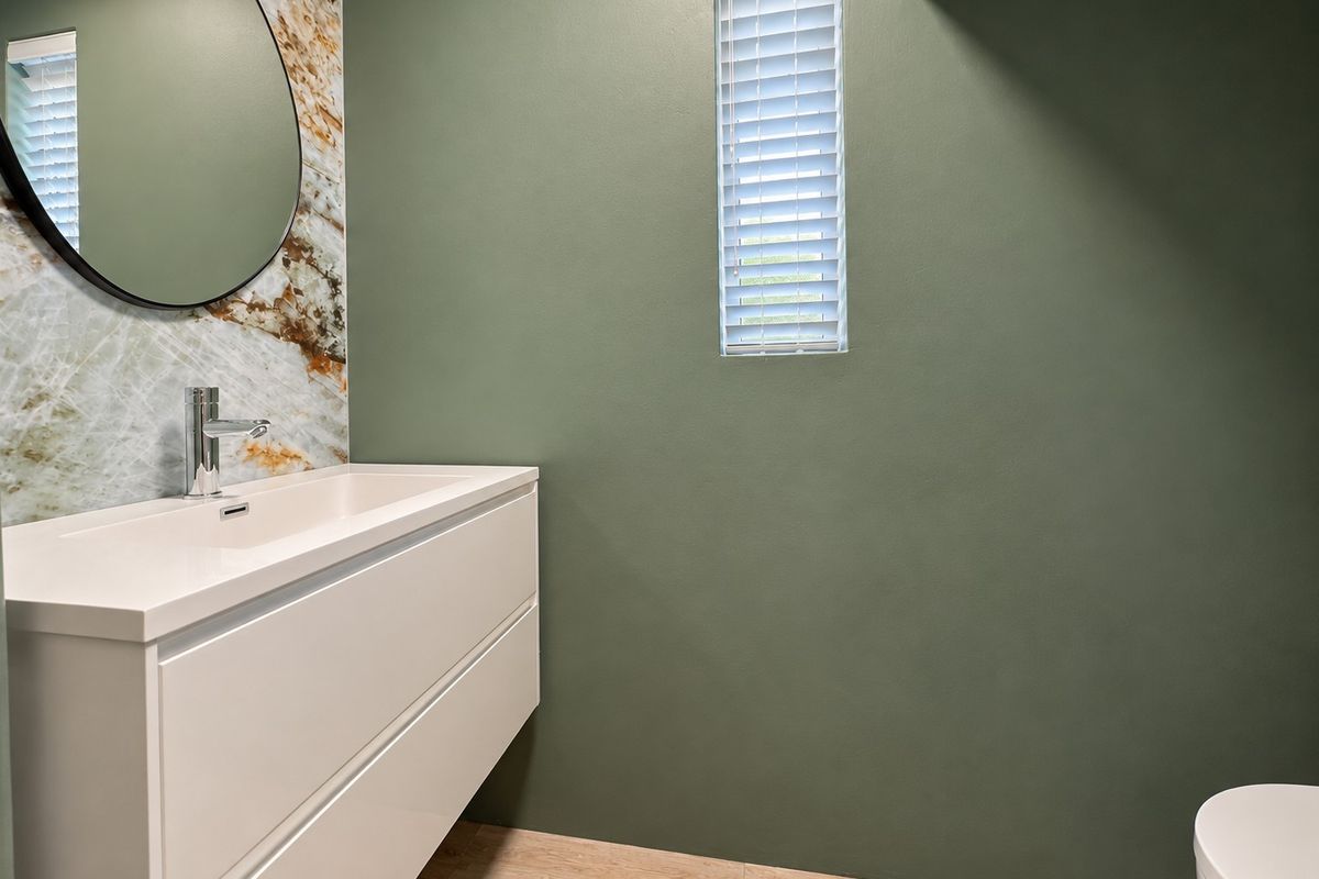 Modern bathroom featuring a wall-mounted vanity with a basin, marble-look splashback, and contemporary green wall finishes.