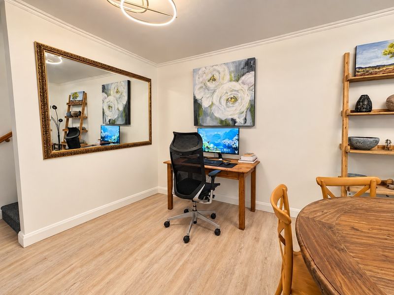 A well-maintained home office space featuring light wood-look laminate flooring, crown molding, and modern recessed lighting, providing a clean and functional work environment.