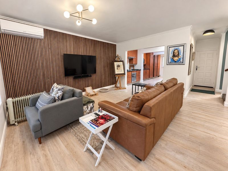 Open-plan living area featuring a modern timber slat feature wall, split-system air conditioning, and a connected kitchen with built-in cabinetry and appliances.