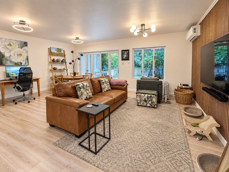 Spacious open-plan living area featuring a wood-slat accent wall, split-system air conditioning, and large sliding glass doors providing access to the garden.