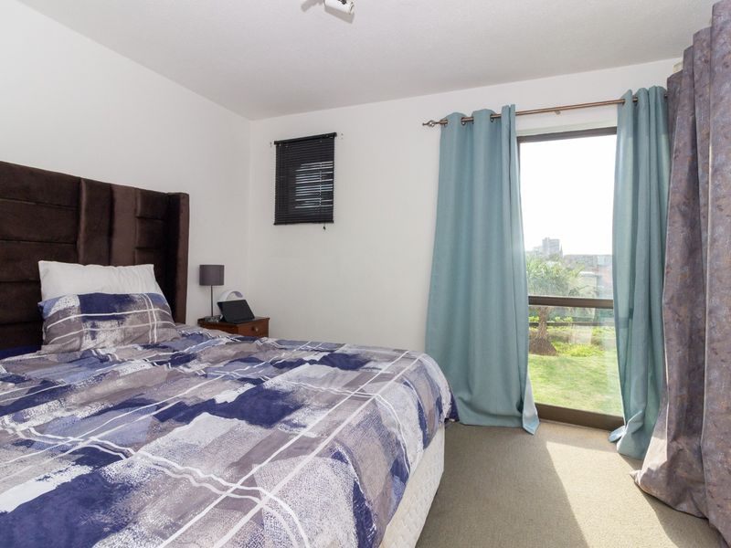 A well-lit bedroom featuring carpeted flooring and a large sliding glass door providing access to the outdoors.