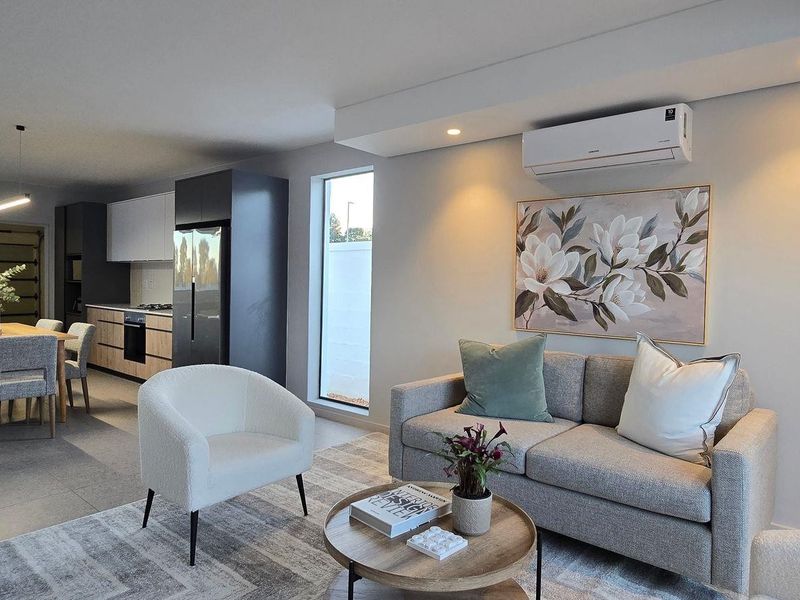 Modern open-plan living and dining area featuring sleek kitchen cabinetry, recessed lighting, and a wall-mounted air conditioning unit.