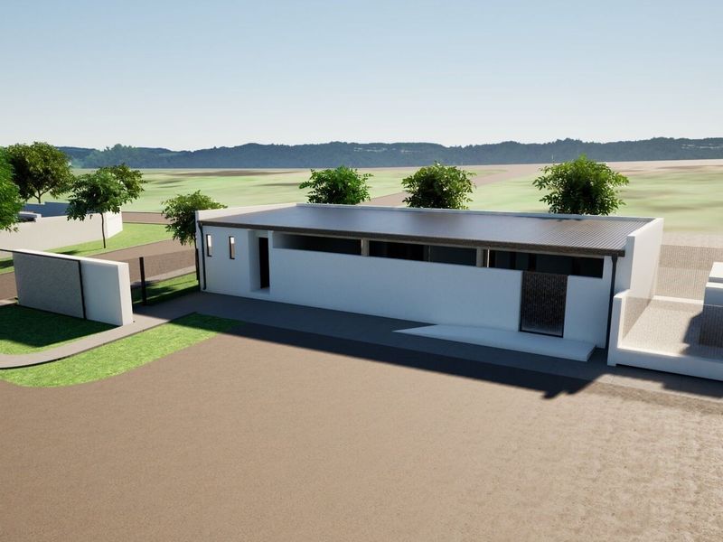 A modern single-story residential property featuring a flat roof, clean white exterior walls, and a paved driveway entrance.