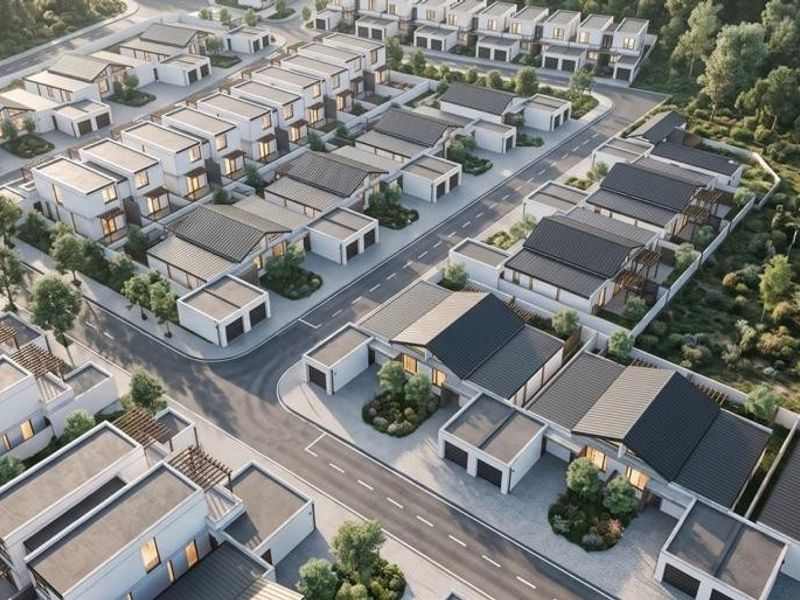 An aerial view of a modern residential estate featuring uniform housing units, paved streets, and landscaped surroundings.