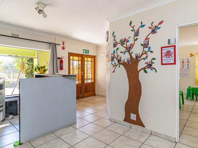 Entrance area featuring tiled flooring, double wooden doors, and direct access to adjacent rooms, currently utilized as a reception space.