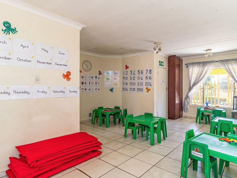 A multi-purpose room currently used as a classroom, featuring tiled flooring, built-in storage, and security bars on the windows.