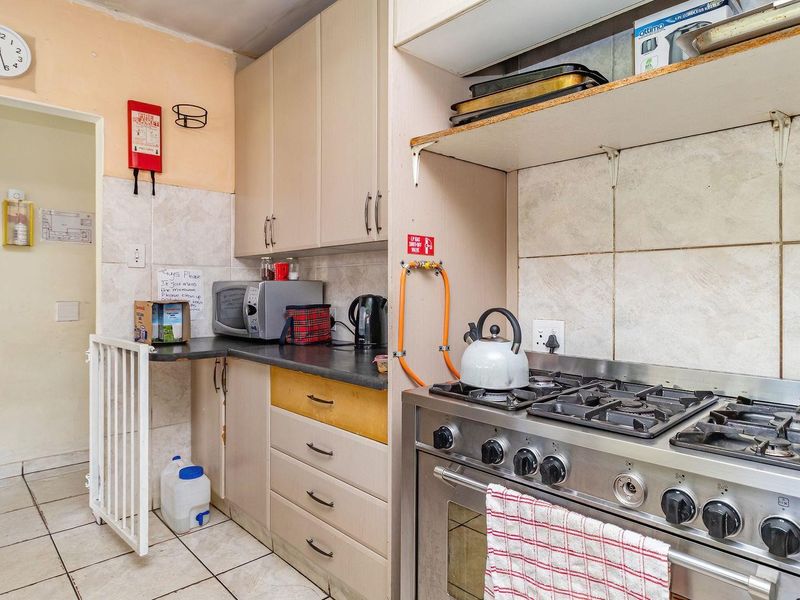 A functional kitchen featuring a gas stove, tiled splashback, and laminate cabinetry, currently showing signs of wear and requiring cosmetic updates.