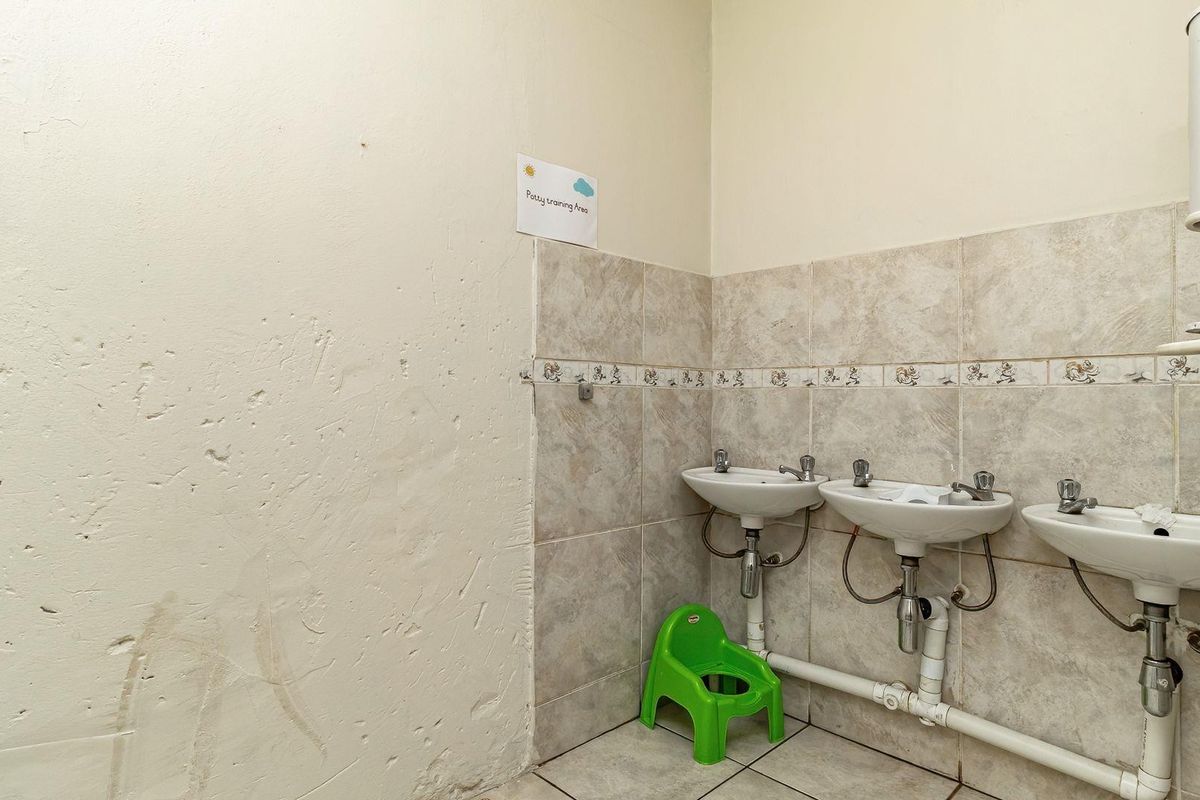 A functional bathroom area featuring three wall-mounted washbasins with tiled splashbacks and exposed plumbing, requiring cosmetic wall repairs.