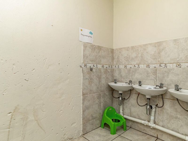 A functional bathroom area featuring three wall-mounted washbasins with tiled splashbacks and exposed plumbing, requiring cosmetic wall repairs.