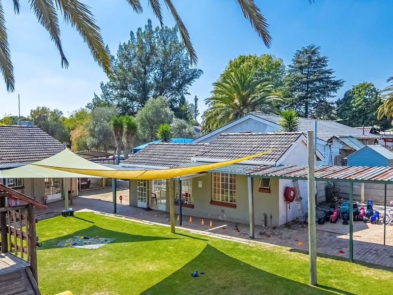 Rear exterior view of the property featuring a lawn, paved patio area with shade sail, and a covered outdoor structure.