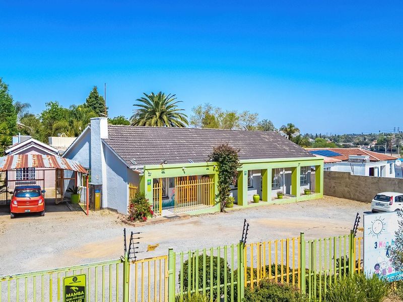 Front exterior view of a single-story property featuring a tiled roof, covered carport, and secure perimeter fencing with an electric gate system.