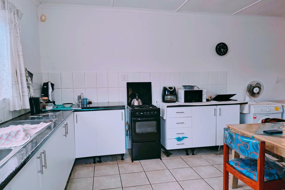 A functional kitchen featuring white cabinetry, tiled backsplash, gas stove with oven, and tiled flooring, offering a practical layout for daily meal preparation.