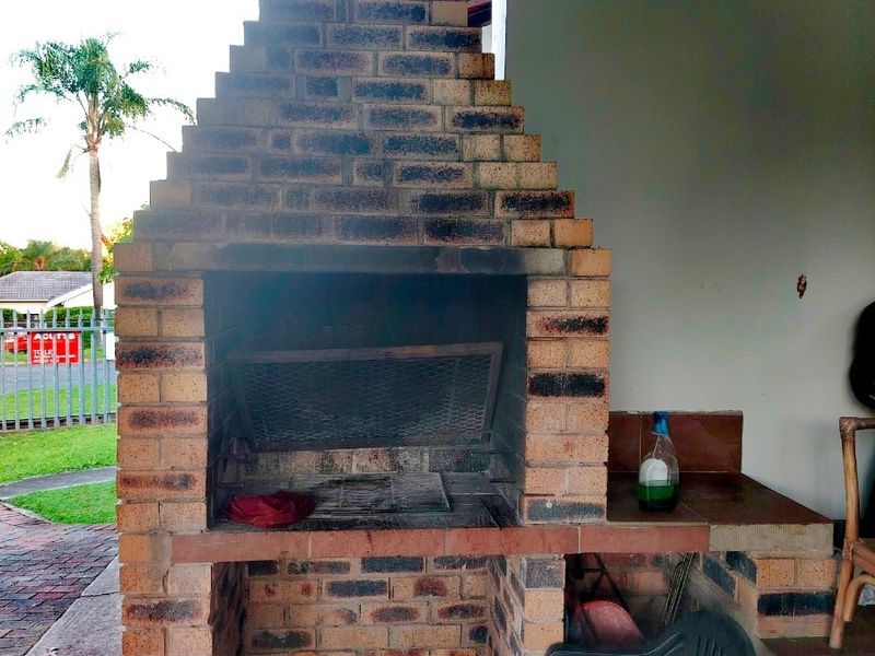 Outdoor patio area featuring a traditional built-in brick braai with a chimney and integrated tiled prep surface.
