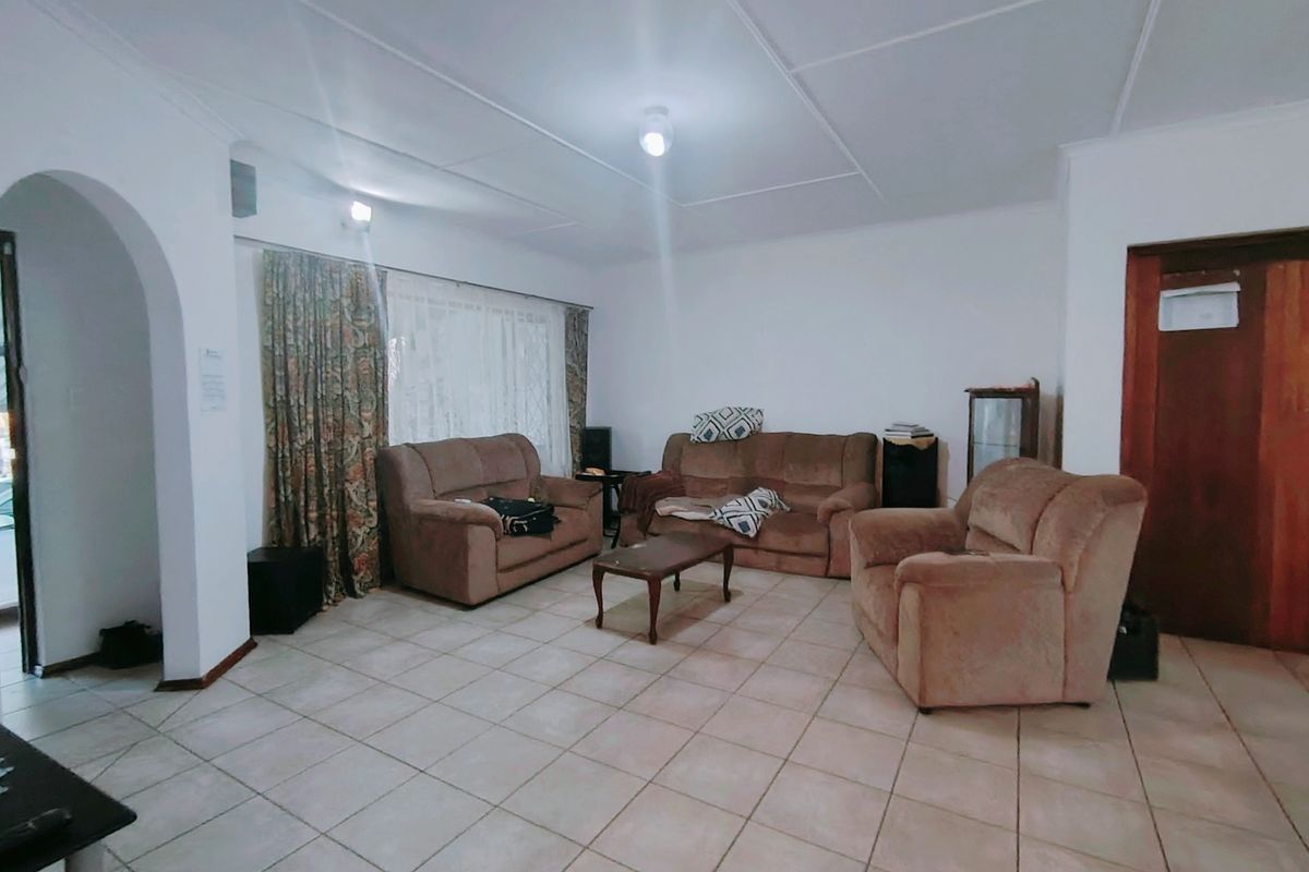 Spacious living room featuring tiled flooring, an arched entryway, and traditional ceiling panels, offering a functional layout ready for modernization.