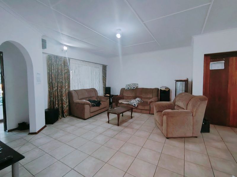 Spacious living room featuring tiled flooring, an arched entryway, and traditional ceiling panels, offering a functional layout ready for modernization.