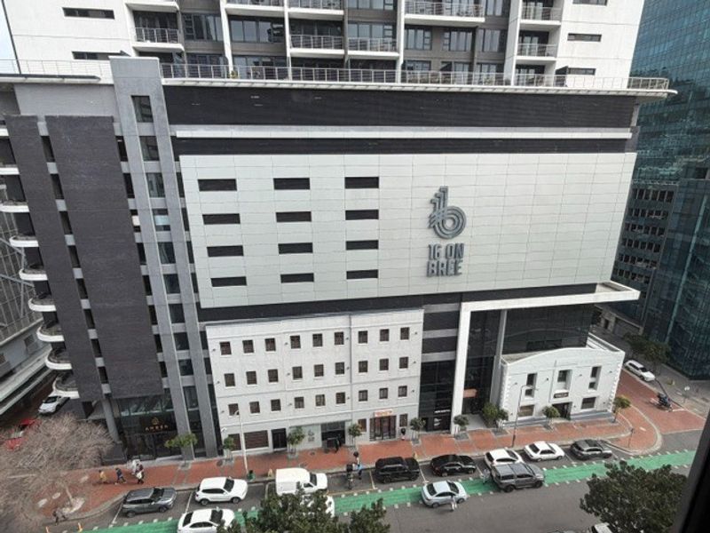 Elevated view of the 16 on Bree office building facade, showcasing modern architectural design, integrated parking levels, and street-level access.