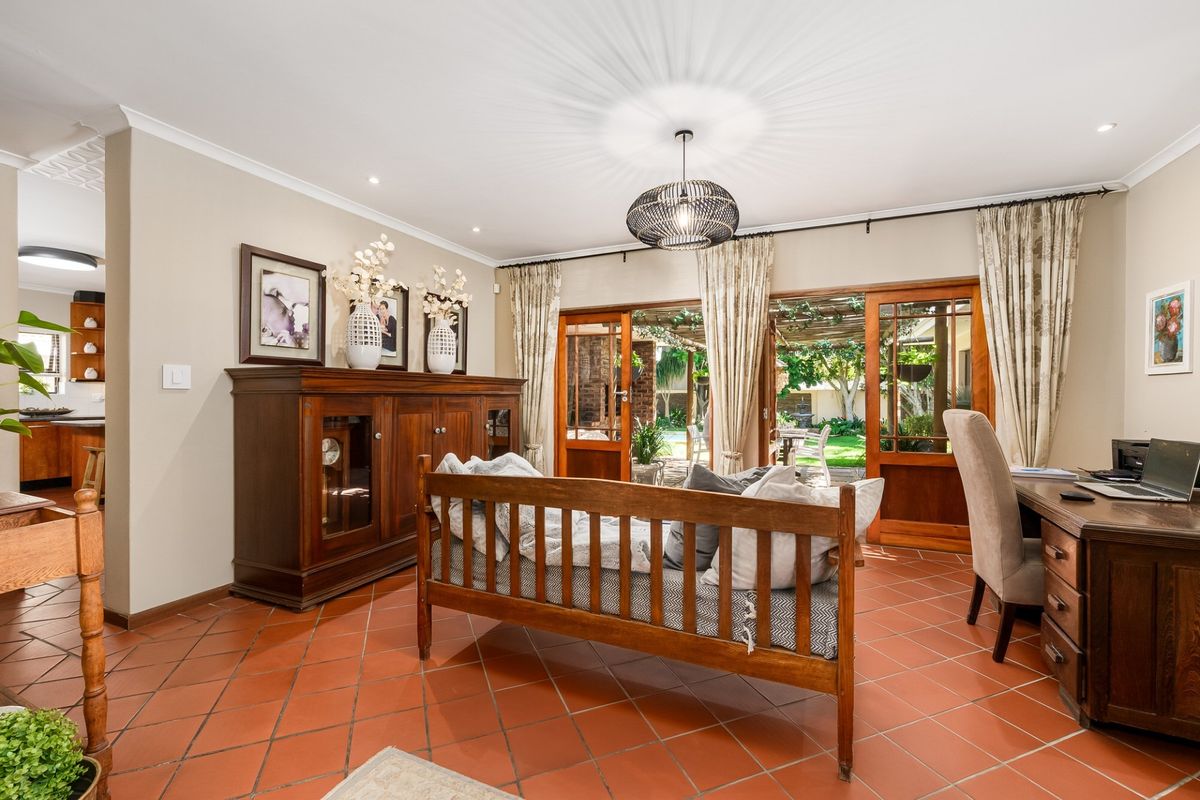 Spacious living area featuring terracotta floor tiles, coved cornicing, and wooden sliding doors providing direct access to the outdoor patio and garden.