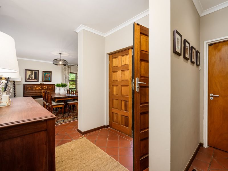 Welcoming entrance hall featuring classic terracotta floor tiles and a solid wooden panelled front door, leading into the adjacent dining area.