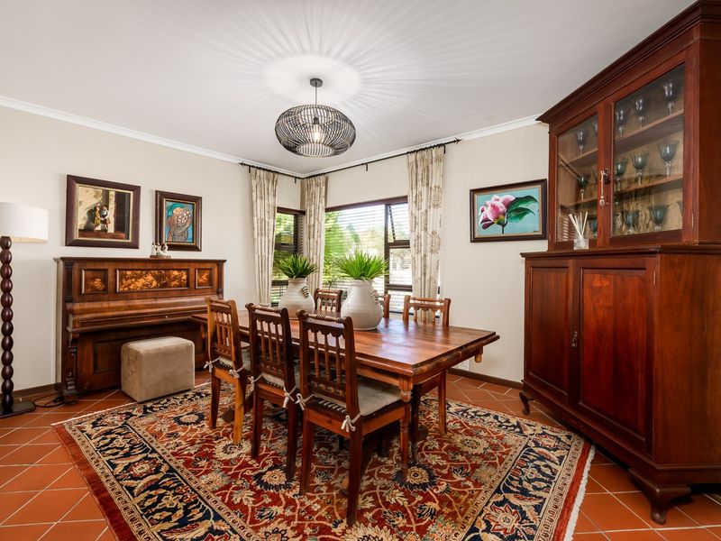 A well-maintained dining room featuring terracotta floor tiles, louvered windows, and classic cove cornicing, providing a warm and traditional atmosphere.